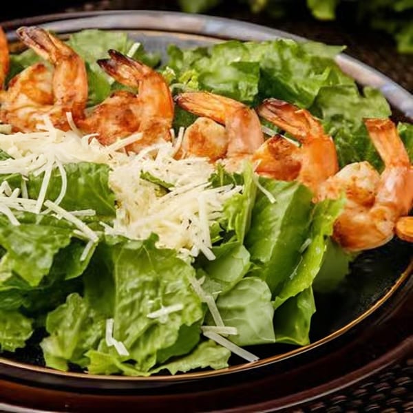 Shrimp Caesar salad with grilled shrimp, crisp romaine lettuce, and shredded Parmesan cheese.