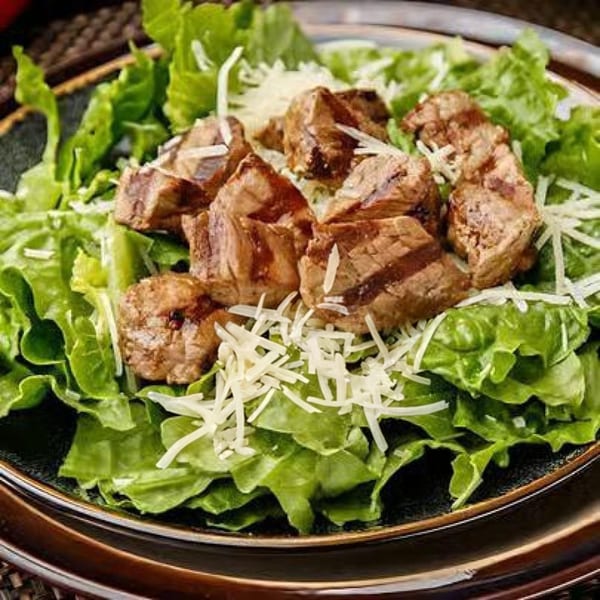 Steak-Out Charbroiled Delivery's steak salad with grilled steak pieces, fresh lettuce, and shredded cheese.